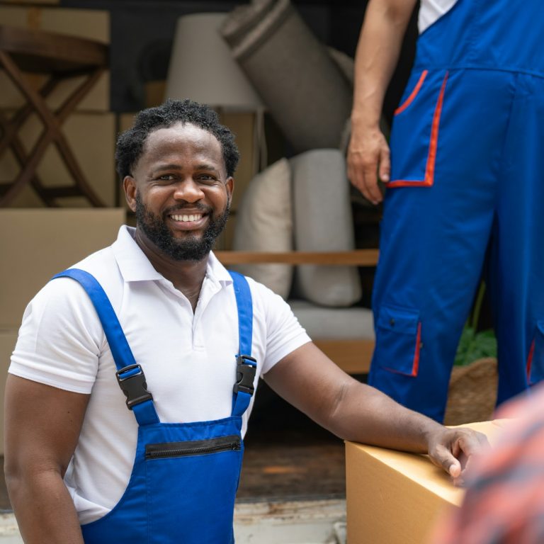 Man mover worker smiling and working prepare to move cardboard boxes and furniture from truck.